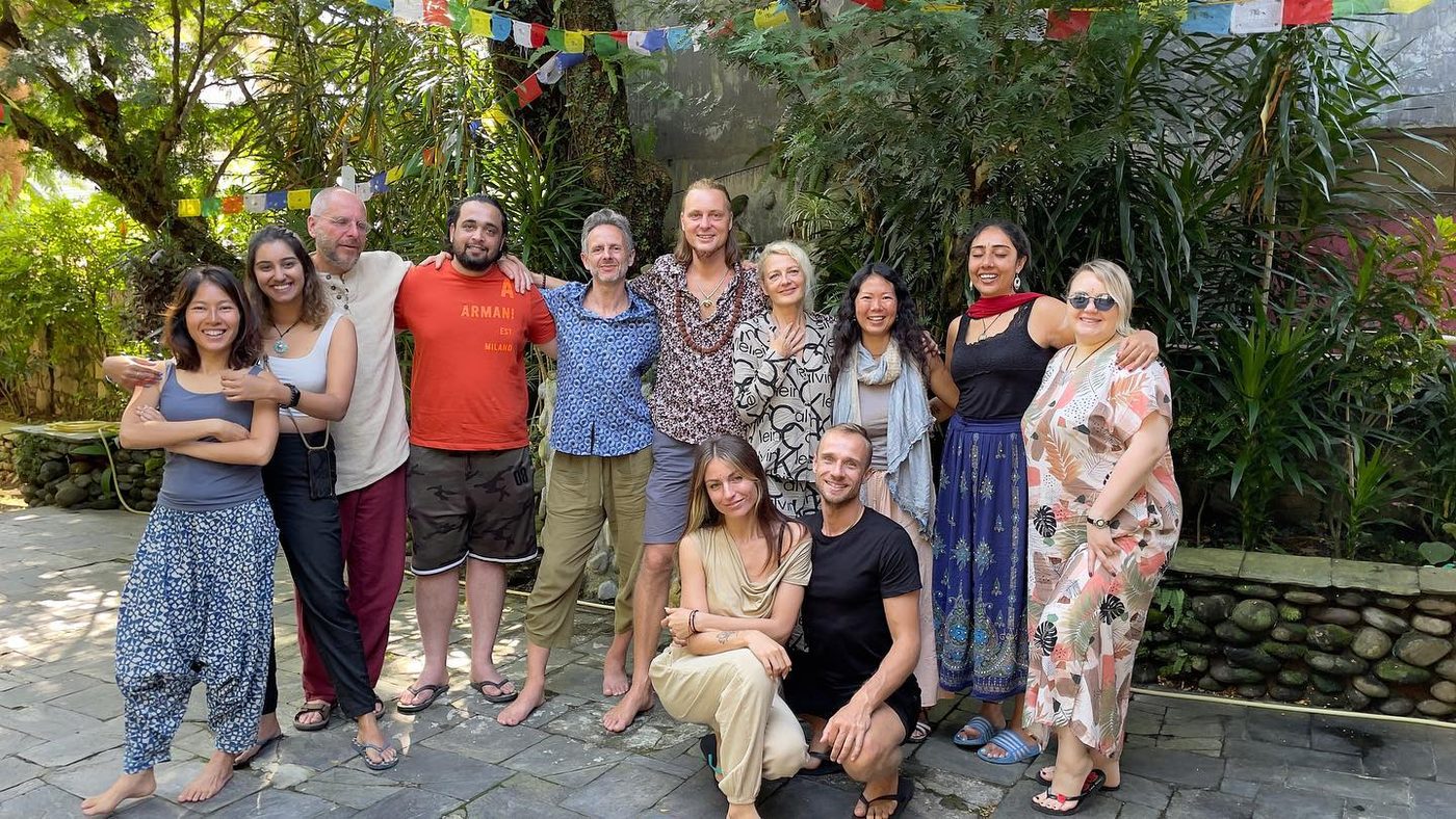 A group of friends posing together in a garden under strings of prayer flags