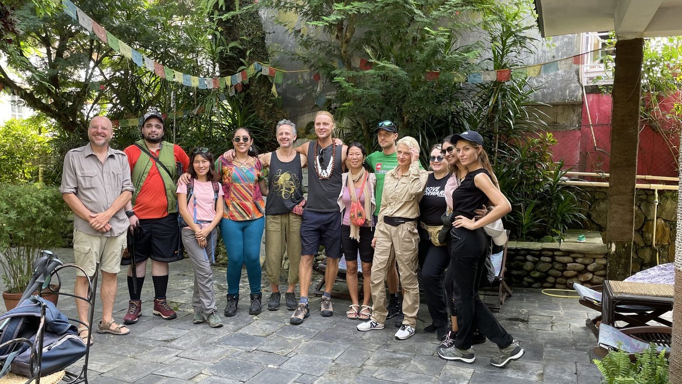 A group of trekkers standing together in a courtyard under strings of prayer flags