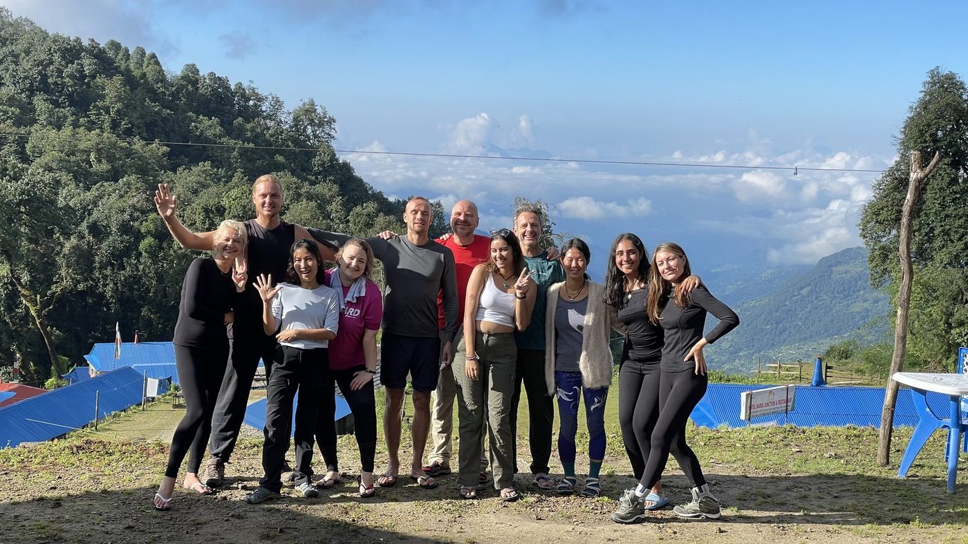 A group of friends laughing and posing together on a sunny ridge above the clouds