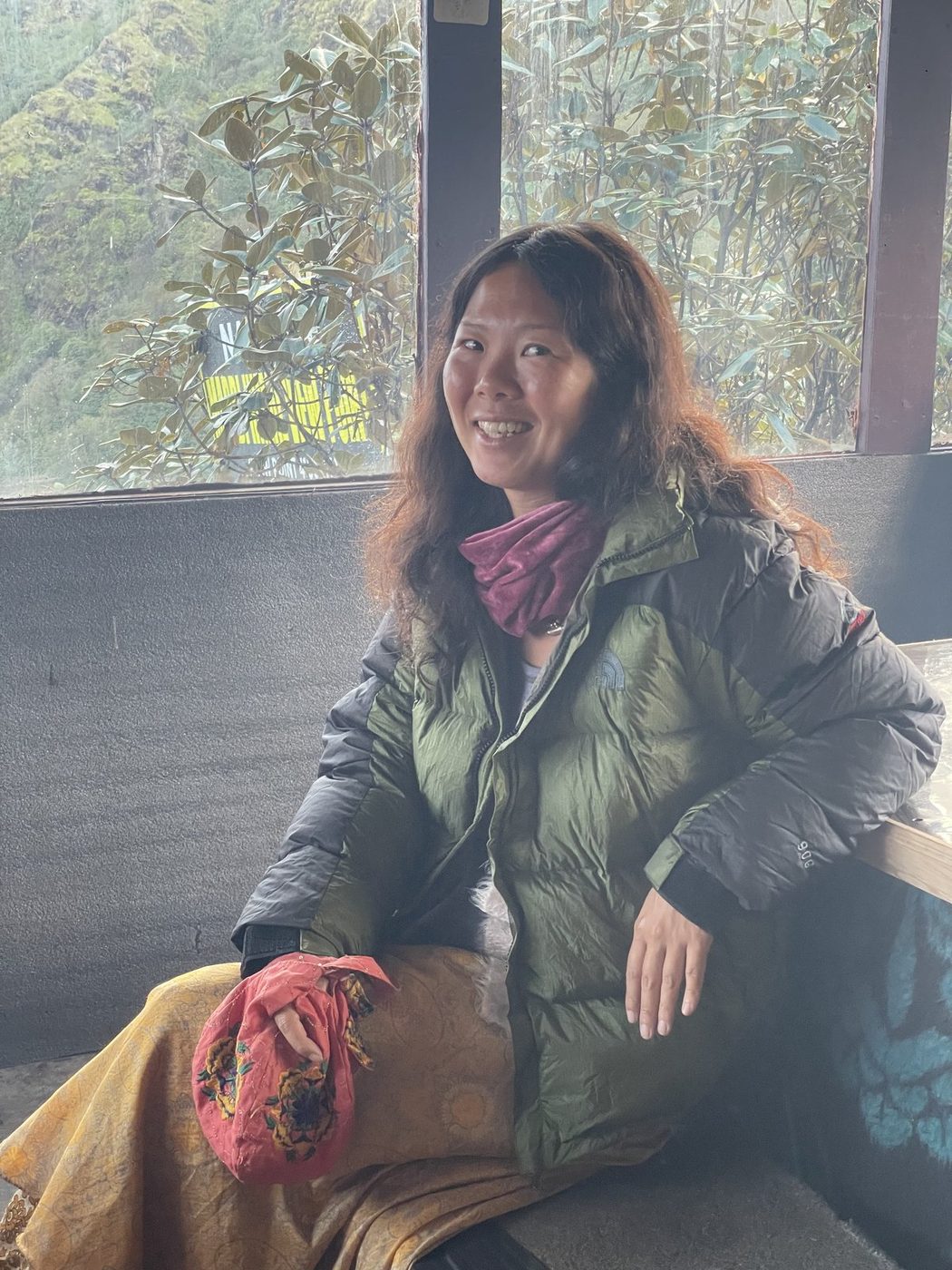 A smiling woman in a green jacket sitting in a lodge window seat