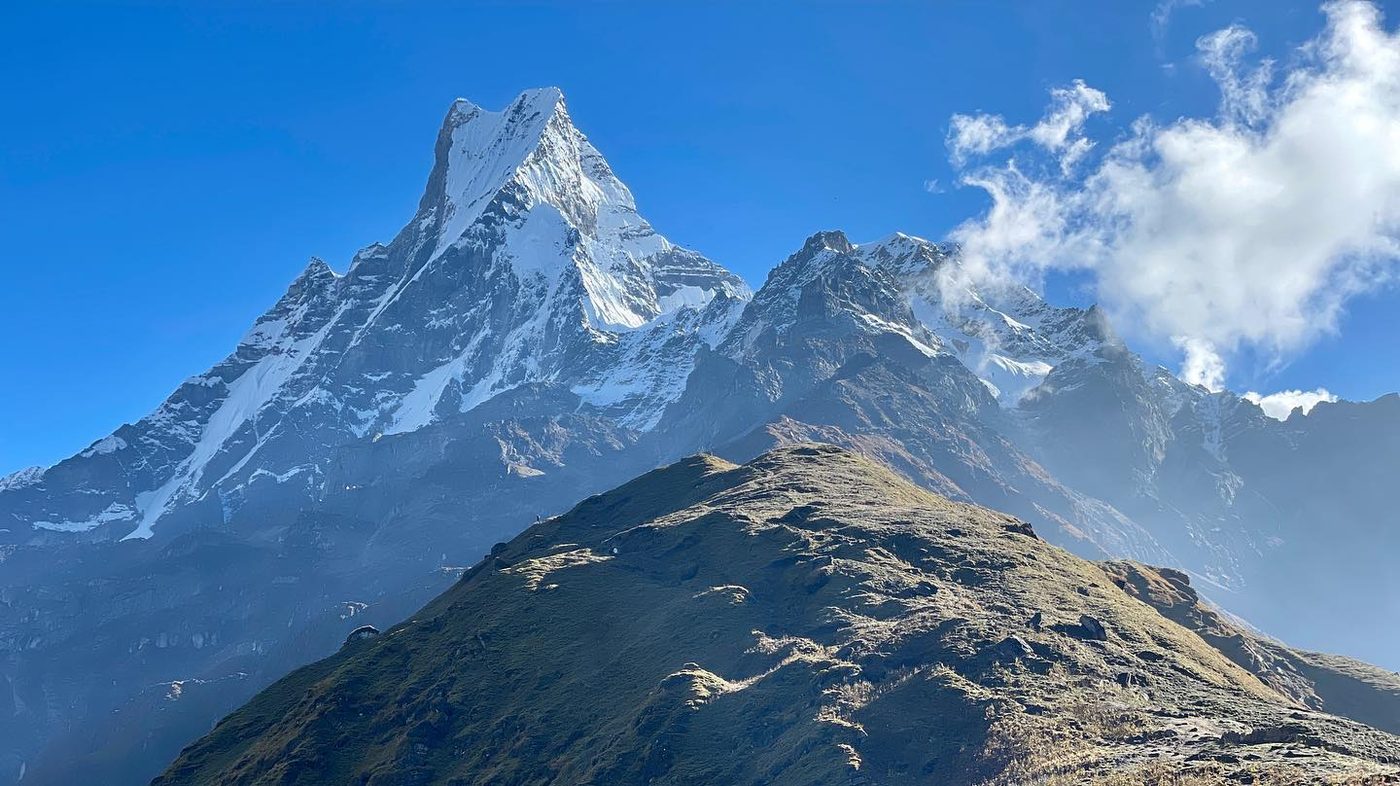 A sharp snow peak seen close up under a deep blue sky