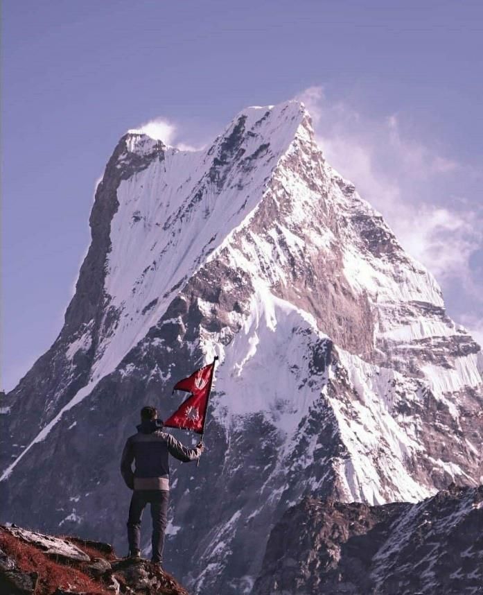 A trekker holding a flag on a snow peak