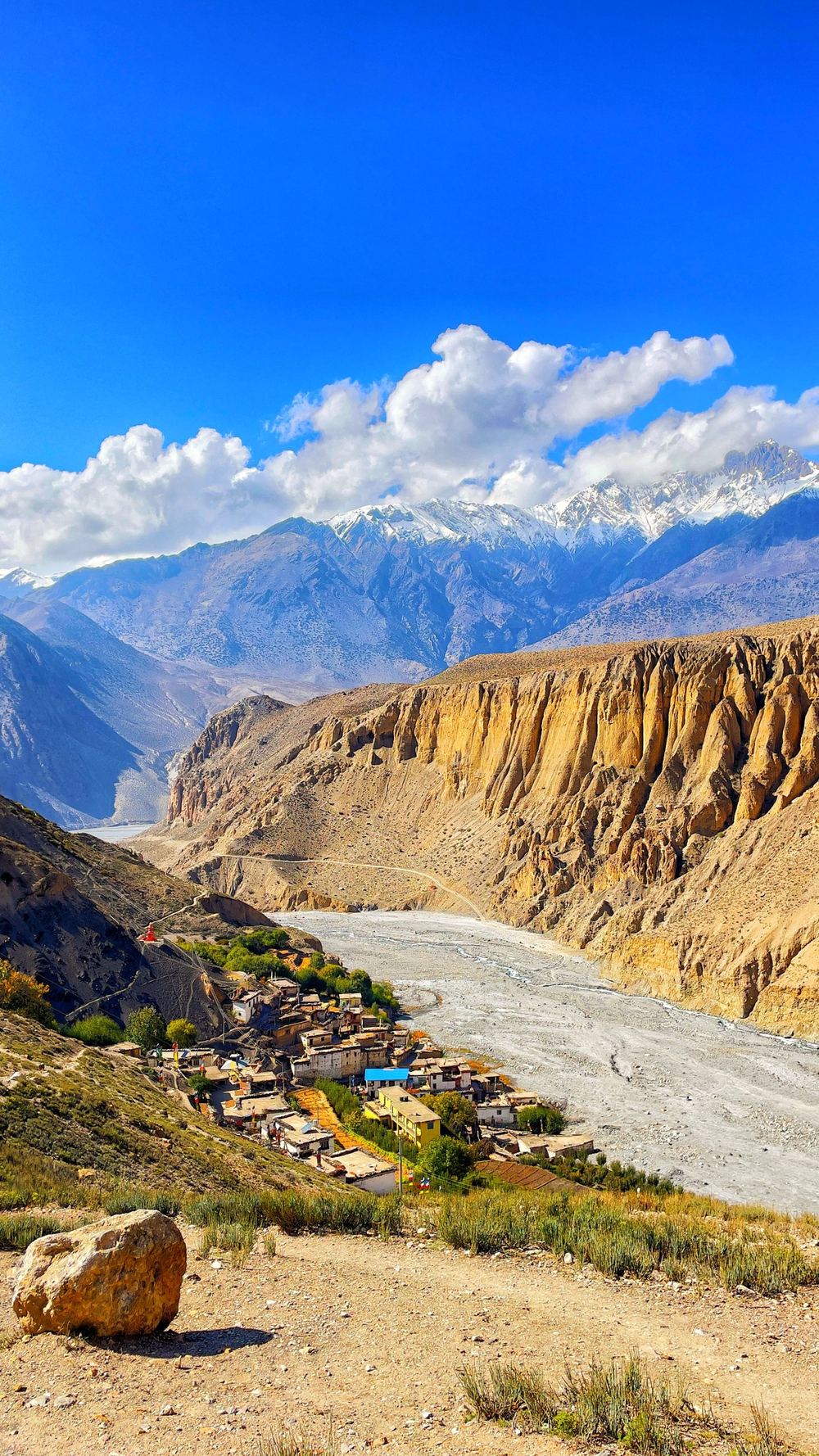 A village in a river gorge below snow mountains